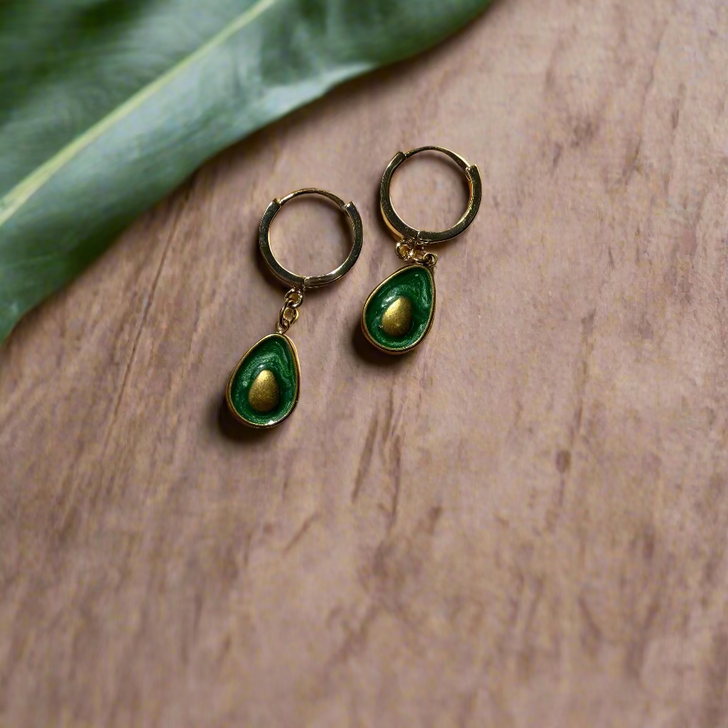 Pair of green and gold earrings on a wooden surface
