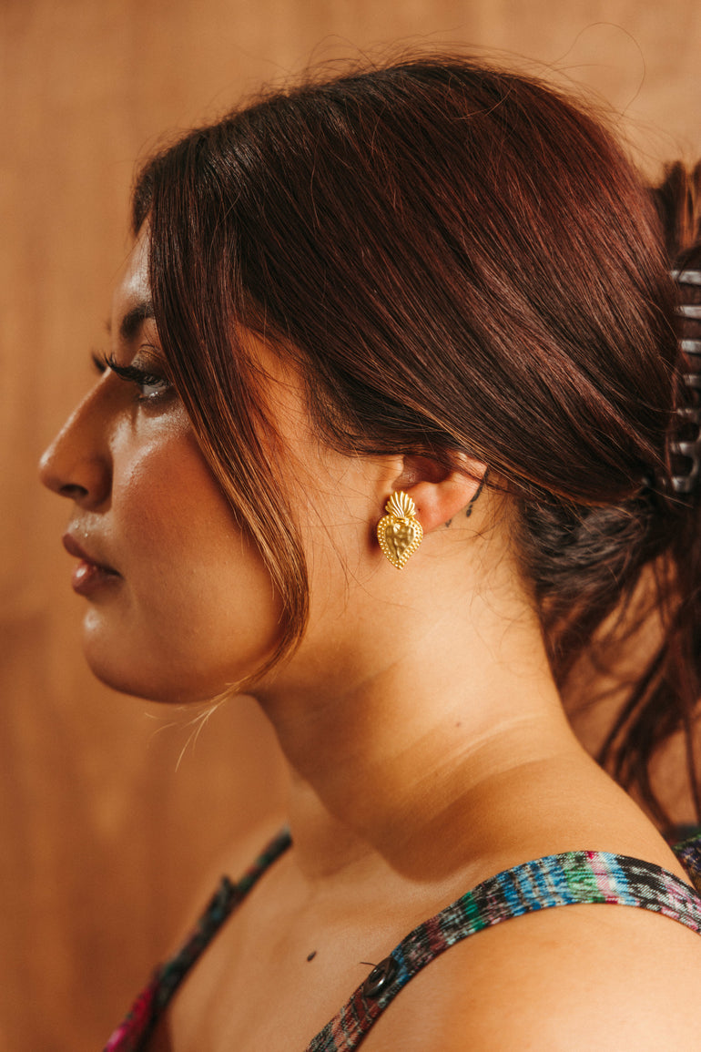 Sacred Heart Latino inspired heart shaped stud gold earrings on a Latina girl with brown skin and brown hair modeling for a Latina small business
