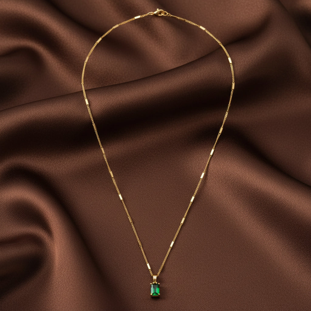 Gold necklace with a green pendant on a white background