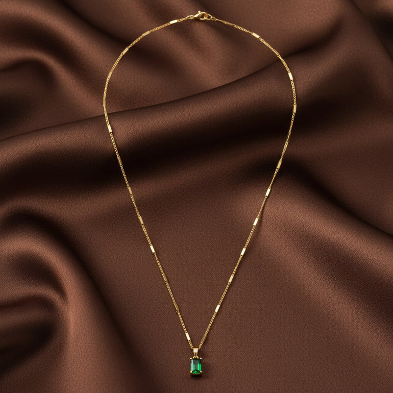 Gold necklace with a green pendant on a white background