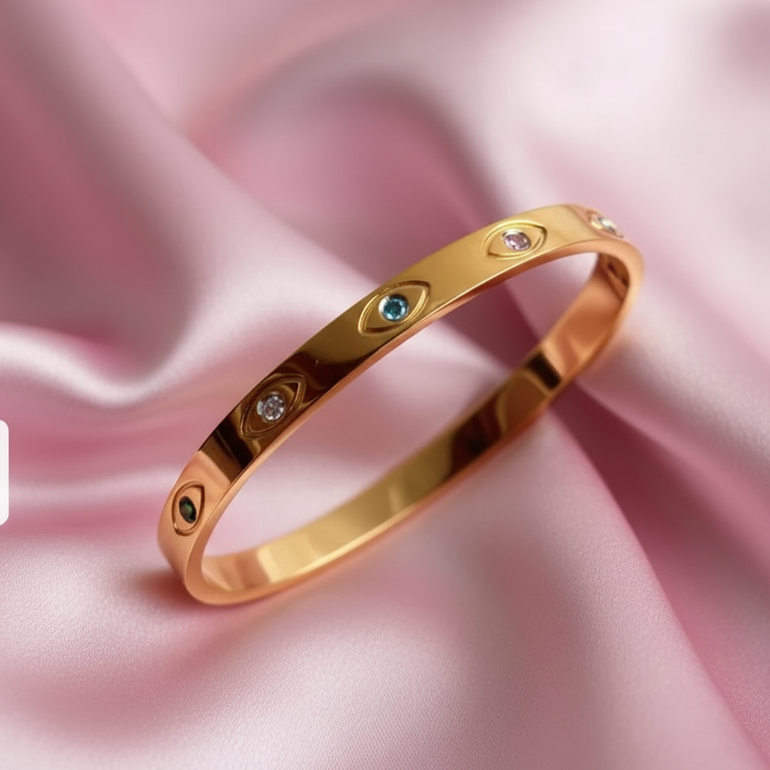 Stay protected and stylish with our Evil Eye Gold Bangle. Made with titanium steel, 18K gold plating, and zircon stones for long-lasting shine. Perfect for daily wear, stacking, and gifting. Shop Latina-owned jewelry at Oreja Linda.