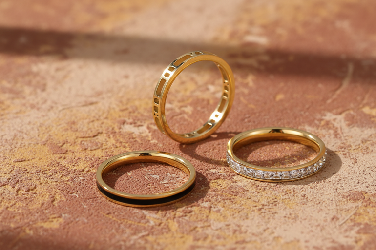 Three gold rings with different designs on a light beige background